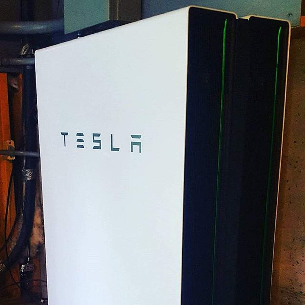 Dua perangkat Tesla Powerwall 2 yang terpasang rapi dalam konfigurasi bertumpuk di dinding sebuah rumah hunian modern.