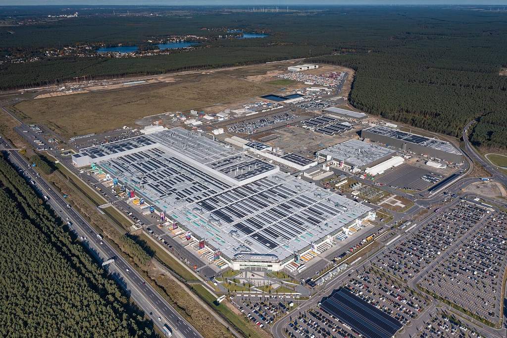 Tampak depan bangunan pabrik Tesla Gigafactory Berlin-Brandenburg di Grünheide, Jerman, dengan area parkir dan lanskap sekitarnya.