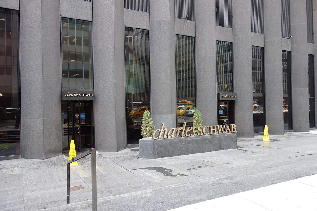 Gedung perkantoran modern Charles Schwab Corporation yang menampilkan logo perusahaan dengan latar belakang kawasan bisnis di Amerika Serikat.
