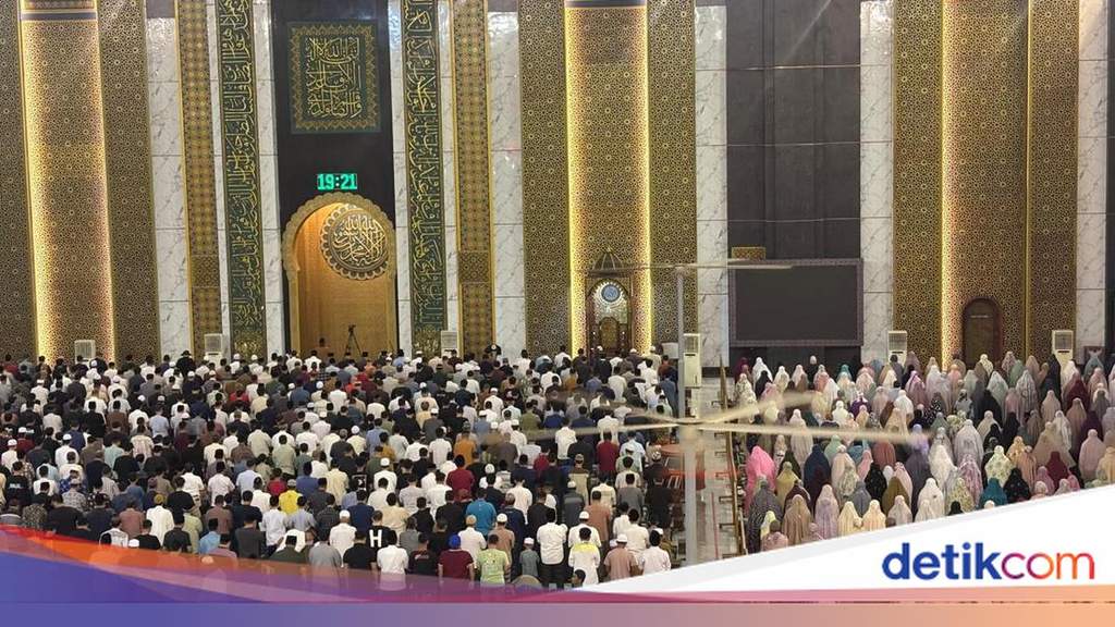 Seorang imam sedang memimpin jamaah melaksanakan salat di dalam masjid dengan saf yang rapi dan khusyuk.