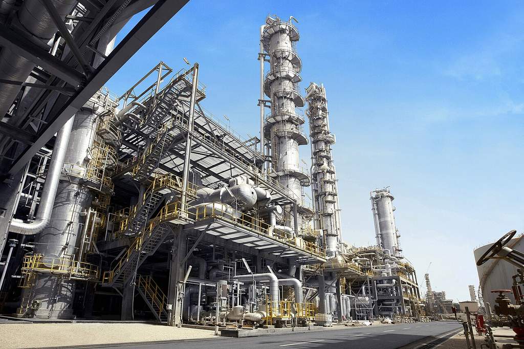 Pemandangan kompleks kilang minyak dan pabrik petrokimia raksasa dengan deretan pipa baja serta menara distilasi modern.