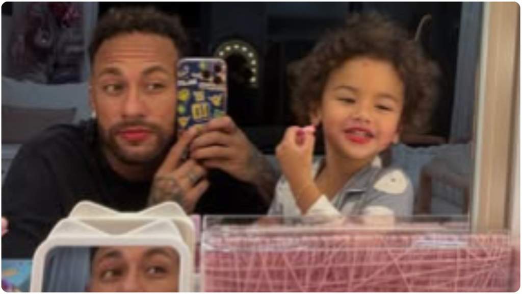 Potret close-up Neymar Jr tersenyum hangat saat menemani putrinya bermain peran dengan memakaikan riasan wajah di rumah.