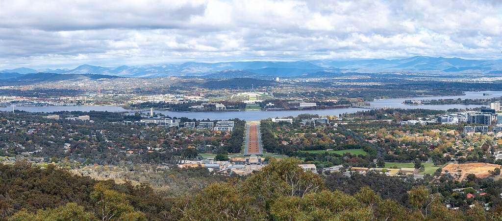 Pemandangan udara kota Canberra yang menunjukkan tata kota terencana dengan latar belakang Danau Burley Griffin dan lanskap pegunungan.