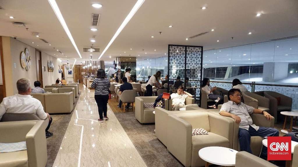 Suasana ruang tunggu atau lounge bandara yang tampak penuh dengan pengunjung yang mengantre di depan meja resepsionis.