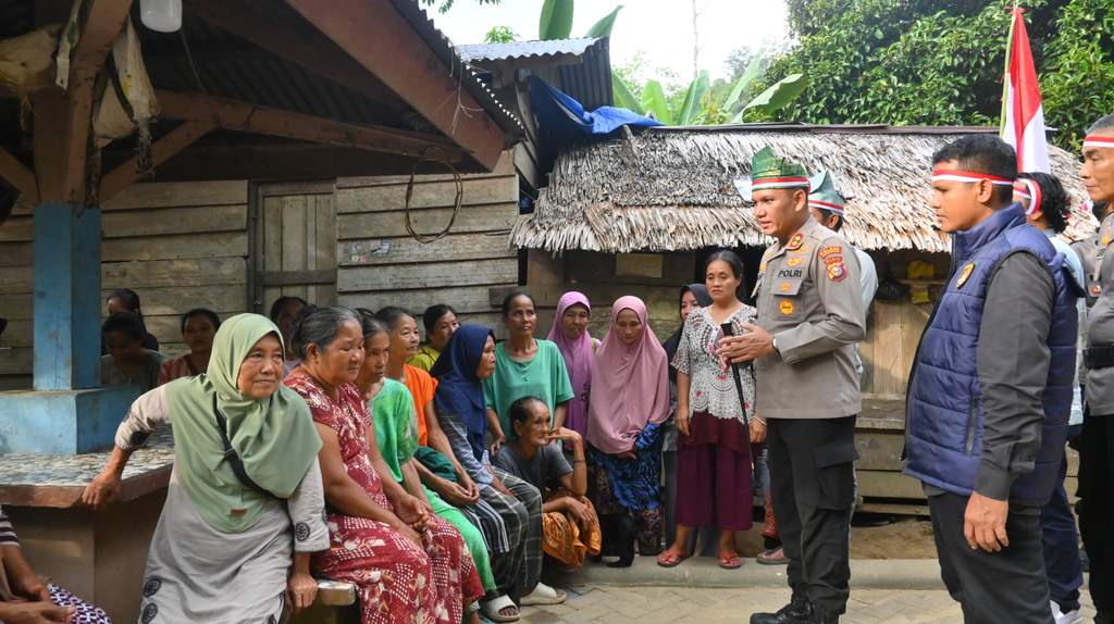 Petugas kepolisian bersama Tim Ekspedisi Merah Putih membagikan bendera kepada masyarakat adat Suku Talang Mamak di kawasan hutan pedalaman.