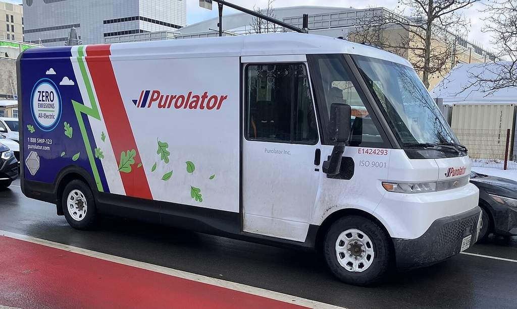 Kendaraan operasional truk pengantar barang elektrik milik perusahaan logistik Purolator yang sedang beroperasi di jalanan kota di Kanada.